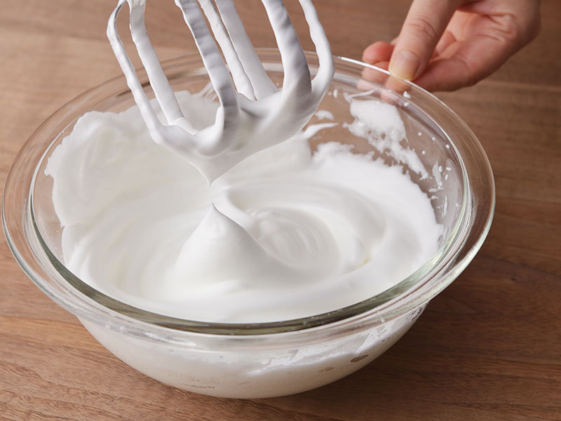 別のボウルに卵白を入れ、残りの砂糖を3回に分けて加えながら、角が立つまで泡立ててメレンゲを作ります。