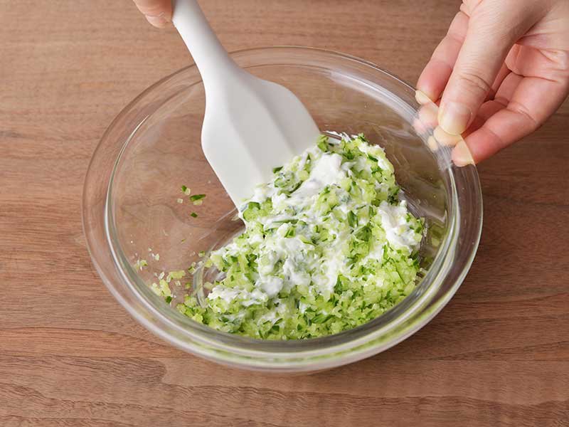 ザジキを作ります。きゅうりはみじん切りにして水けをしぼり、ヨーグルト、にんにく、塩とよく混ぜ合わせます。