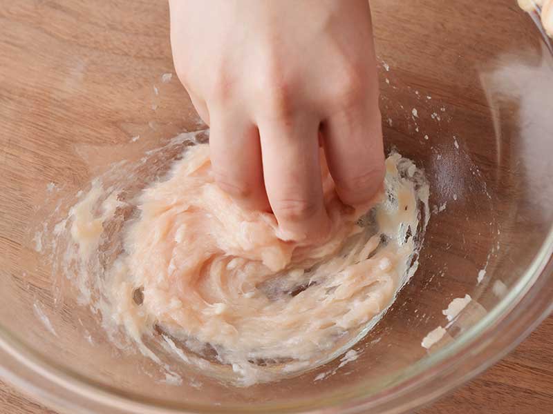 かに風味かまぼこはみじん切りにします。ボウルに鶏肉を入れて、粘りが出るまでしっかり練り混ぜます。
