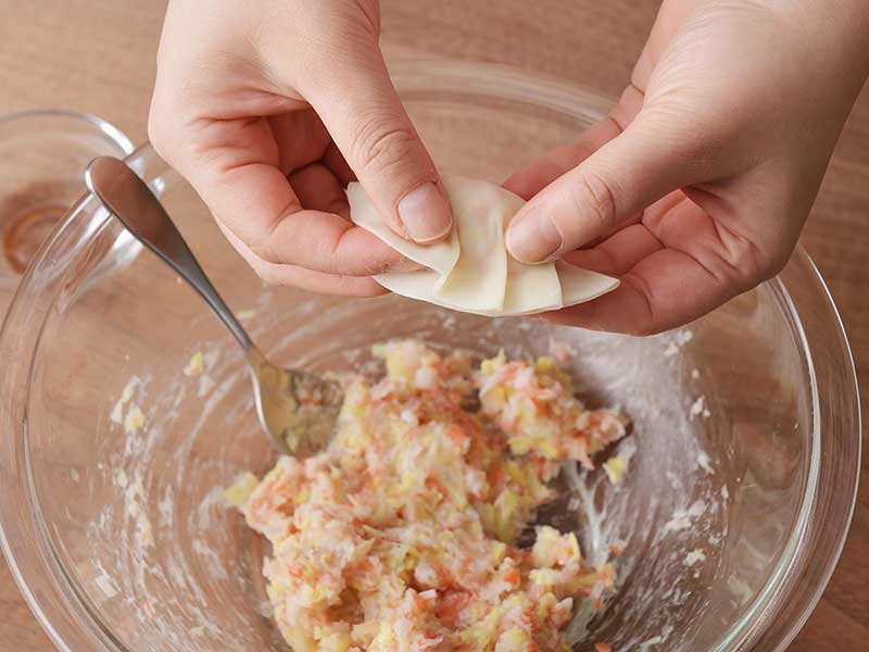 3のたねを1人7個になるように等分し、餃子の皮にのせます。皮の縁に水(分量外)をつけ、ひだを付けながら閉じます。